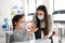 Teacher and children with face mask back at school, disinfecting hands.