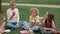 Teacher eating food with class of multiracial kids outdoors