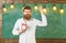 Teacher in eyeglasses holds alarm clock. Schedule and regime concept. Bearded hipster holds clock, chalkboard on