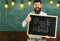 Teacher in eyeglasses holds blackboard with inscription back to school. Man with beard on happy face welcomes students