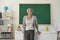 A teacher with gray hair teaches standing in a school class