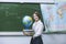 Teacher happy young woman in the class with a globe and books on