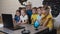 Teacher helping caucasian children at computer terminal in primary school. Smiling school kids using computer with