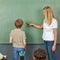 Teacher helping child at chalkboard