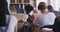 Teacher helping a learning student asking a question by raising her hand, in classroom at her desk. Education, study and