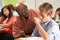 Teacher Helping Male Pupil Studying At Desk In Classroom