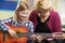 Teacher Helping Pupil To Play Guitar In Music Lesson