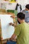 Teacher helping student in art scholl, student with protective mask drawing picture