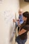 Teacher helping student with a math problem on a whiteboard.