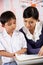 Teacher Helping Student Working At Desk