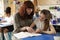 Teacher helps a girl at her desk, close up both looking down