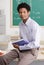 Teacher holding school book posing in classroom