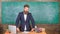 Teacher interesting interlocutor as authority. Teacher charismatic hipster stand near table classroom chalkboard