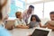 Teacher among kids with computers in elementary school class