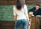 Teacher looking through his glasses at beautiful young student standing in front of rostrum. Young girl rear view