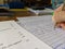 A teacher marking an exam paper at a desk