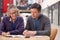 Teacher With Mature Male Adult Student Sitting At Table Working In College Hall