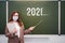 Teacher in a medical mask at the blackboard with an indeterminate year of the end of quarantine. Concept of problems at school