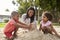 Teacher At Montessori School Playing With Children In Sand Pit