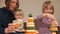 Teacher plays pyramids with children on table. She holds the baby in her arms.