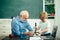 Teacher and pupil learning together in school. Happy cute Grandson and Grandfather sitting at a desk indoors. Elementary