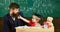 Teacher and pupil in mortarboard, chalkboard on background. Kid cheerful distracting while studying, attention deficit