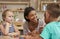 Teacher And Pupils Using Wooden Shapes In Montessori School