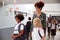 Teacher And Pupils Walking Along Corridor In Busy Elementary School Corridor