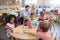 Teacher And Pupils Working At Tables In Montessori School