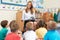 Teacher Reading Book To Elementary School Class