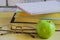 Teacher's Day concept and back to school, green Apple, book, laptop, reading glasses and pen on wooden table, sunlight