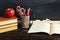 Teacher`s desk with writing materials, a book and an apple, a blank for text or a background for a school theme. Copy space