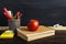 Teacher`s desk with writing materials, a book and an apple, a blank for text or a background for a school theme. Copy space