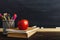 Teacher`s desk with writing materials, a book and an apple, a blank for text or a background for a school theme. Copy space
