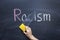 The teacher`s hand erases the word Racism from the chalkboard