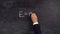 The teacher`s hand writes the formula E=mc2 on the blackboard.