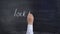 The teacher`s hand writes the word LOCKDOWN on a chalkboard.