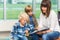 Teacher With Schoolboys Reading Book In Library