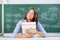 Teacher With Stack Of Books Looking Up At Classroom Desk