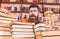 Teacher or student with beard sits at table with books, defocused. Bibliophile concept. Man on confused face between