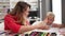 Teacher and toddler drawing on paper high five at classroom