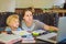 A teacher, a tutor for home schooling and a teacher at the table. Or mom and daughter. Homeschooling