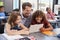 Teacher using tablet with two pupils in school class