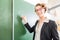 Teacher writing with chalk in front of school class on board