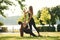 Teaching how to do exercises. Two women in sport clothes are doing exercises outdoors on the field