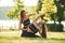 Teaching how to do exercises. Two women in sport clothes are doing exercises outdoors on the field