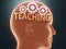 Teaching inside human mind - pictured as word Teaching inside a head with cogwheels to symbolize that Teaching is what people may