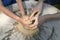 Teaching of wheel throwing. Potter hand correcting child s ones during shaping clay on a potter wheel