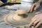 Teaching of wheel throwing. Potter hand correcting child s ones during shaping clay on a potter wheel