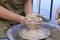 Teaching of wheel throwing. Potter hand correcting woman ones during shaping clay blank on the potters wheel